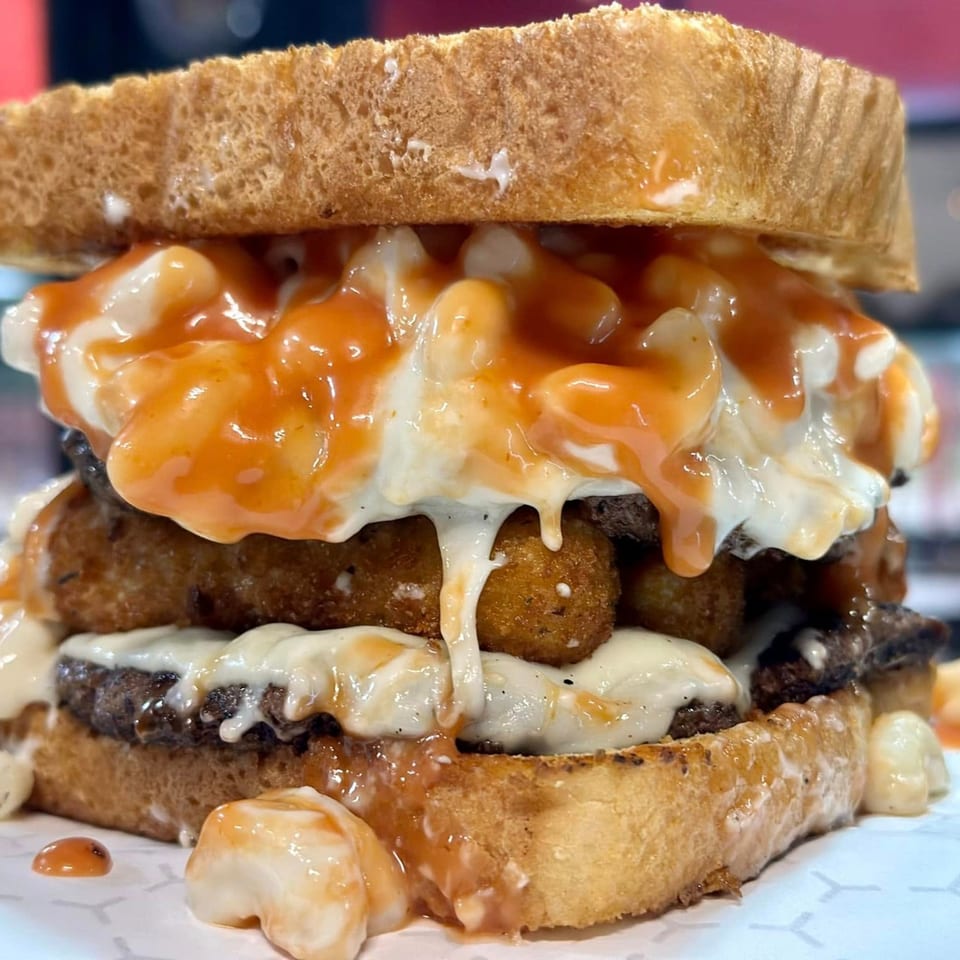 Market Street Burgers' burger with mac and cheese, tater tots, and sauce on toasted bread.