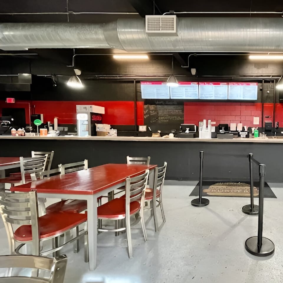 Interior of Market Street Burgers with red tables, metal chairs, and a counter with menu boards.