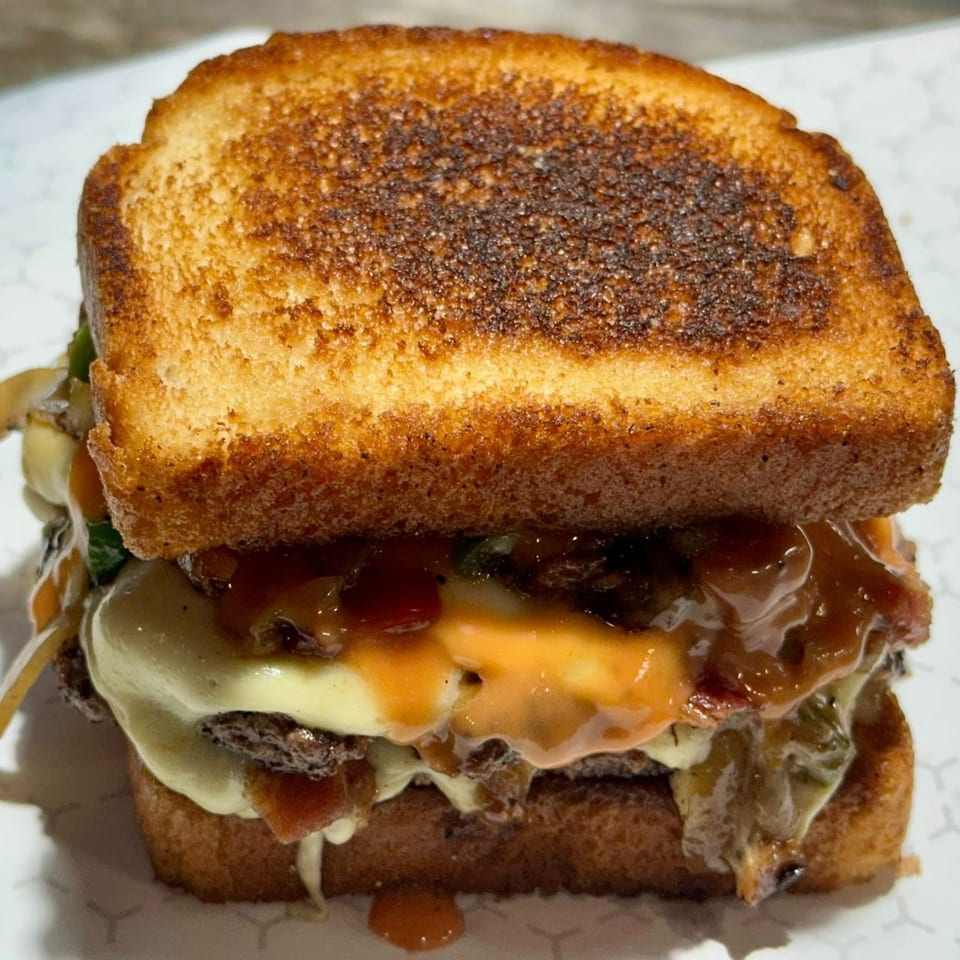 Market Street Burgers' patty melt with melted cheese, bacon, and sauce on toasted bread.